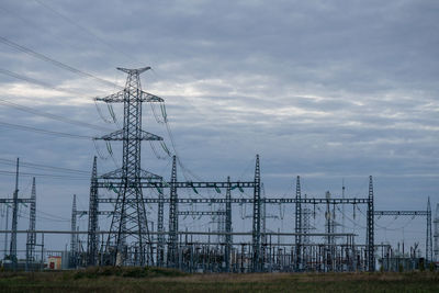 Low angle view of electricity pylon on field against sky