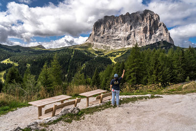 Rear view of man walking on mountain against sky