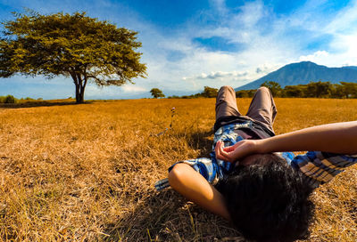 High angle view of woman lying on field against sky