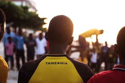 Rear view of people standing at beach against sky