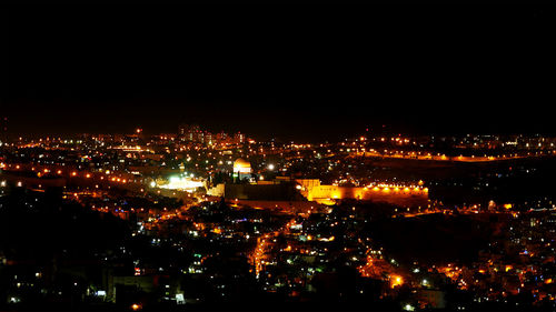 Illuminated cityscape against sky at night