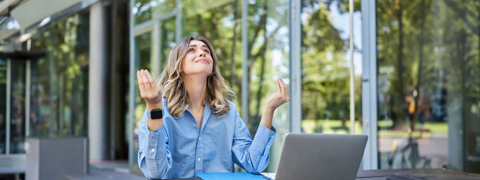 Young woman using mobile phone while sitting on table