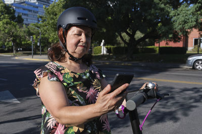 Woman with electric push scooter looking at mobile phone