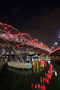 Illuminated bridge over river against sky at night