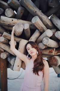 Portrait of woman standing against wooden logs
