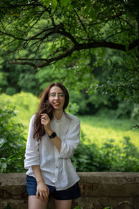 Young woman standing against trees