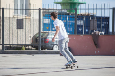 Young man skateboarding on footpath on sunny day