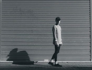 Portrait of young man standing against closed shutter on street