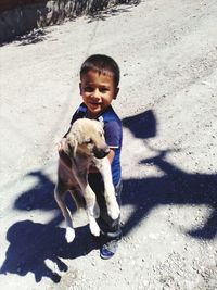 Boy carrying puppy while standing on street