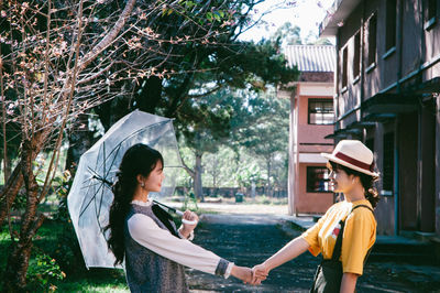 Friends shaking hands against houses and trees