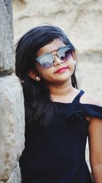 Portrait of girl in sunglasses by wall