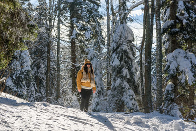 Full length photo of woman wearing winter clothes, hiking in snowy winter forest