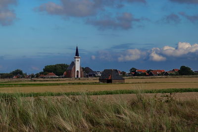 Built structure on field by buildings against sky