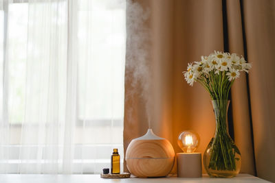 Aromatherapy concept. aroma oil diffuser on the table against the window.