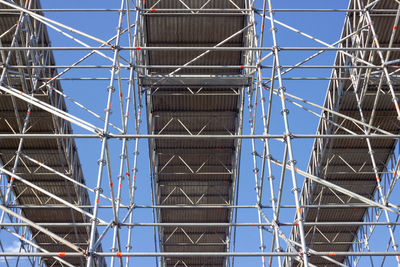 Low angle view of scaffolding bridge against blue sky