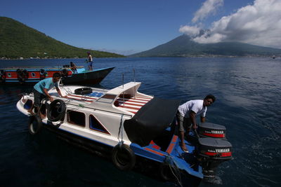 People on boat in sea against sky