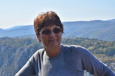 Woman wearing sunglasses against mountains