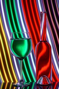 Glass wine and bottle against neon background