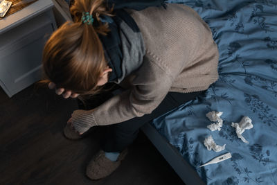 High angle view of sick woman sitting on bed