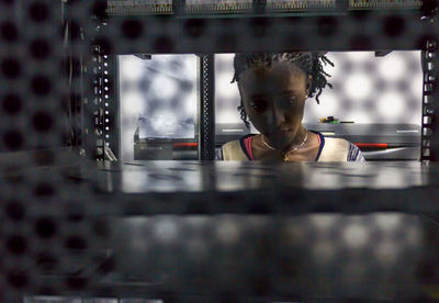 Young woman seen through metal grate