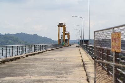 Walkway by bridge against sky