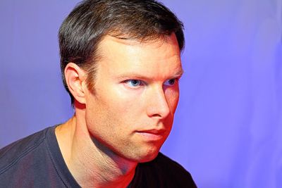 Close-up of thoughtful man against purple background