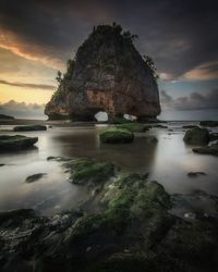 Rock formations by sea against sky during sunset