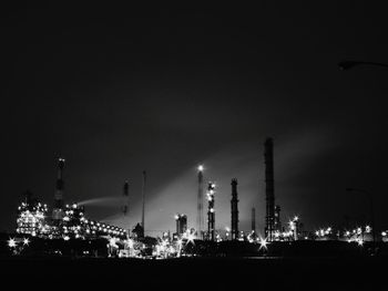 Low angle view of illuminated industry building against clear sky at night