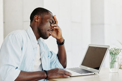 Side view of man using laptop at home