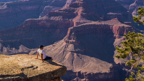 Man sitting on rock by mountains