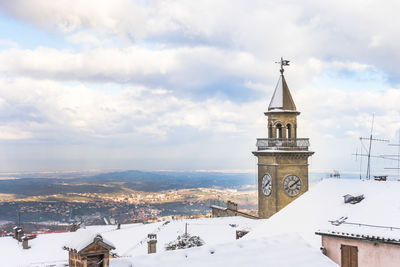 Borgo maggiore tower amidst buildings against sky during winter