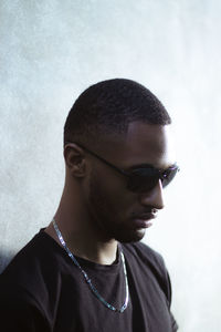 Young man wearing sunglasses against wall