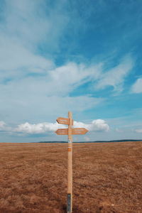 Close-up of road sign on field against sky