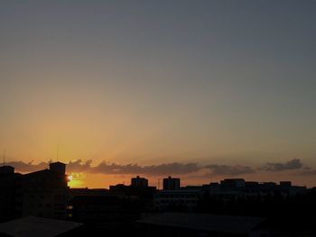 Silhouette buildings against sky at sunset