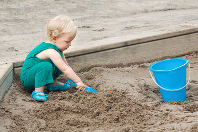 Child baby in sandbox playing with beach toys. girl toddler digging sand and building sandpie.