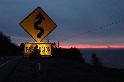 Road sign against cloudy sky at dusk