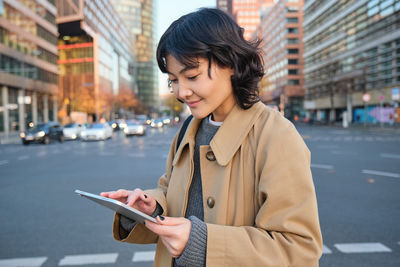 Young woman using mobile phone in city