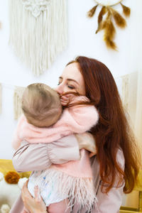 Young mother is holding her little daughter in hands. candid family portrait.