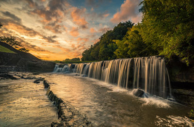 Scenic view of waterfall against sky during sunset