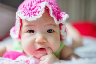 Portrait of cute baby girl with finger in mouth