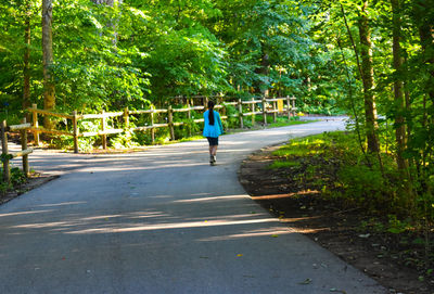 Woman walking on road along trees