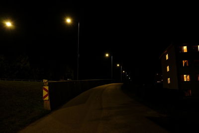 Empty road along illuminated street lights at night