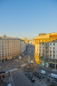 Road amidst buildings against clear sky in city