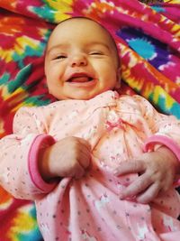 Close-up of smiling baby girl lying on bed
