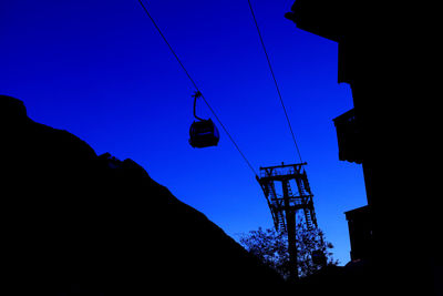 Low angle view of overhead cable car against blue sky