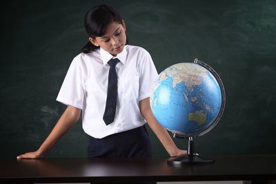 Schoolgirl with globe against blackboard