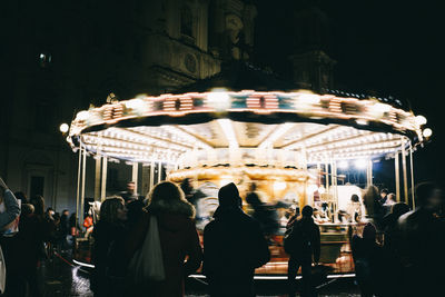 People at illuminated street in city at night
