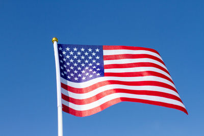 Low angle view of flags against clear blue sky