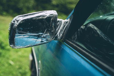 Close-up of side-view mirror wrapped with plastic