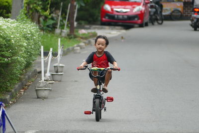 Side view of boy riding bicycle on road